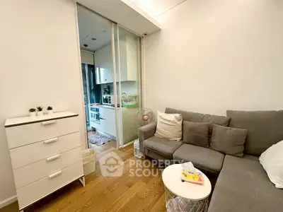 Cozy living room with modern sofa and open kitchen layout in compact apartment.