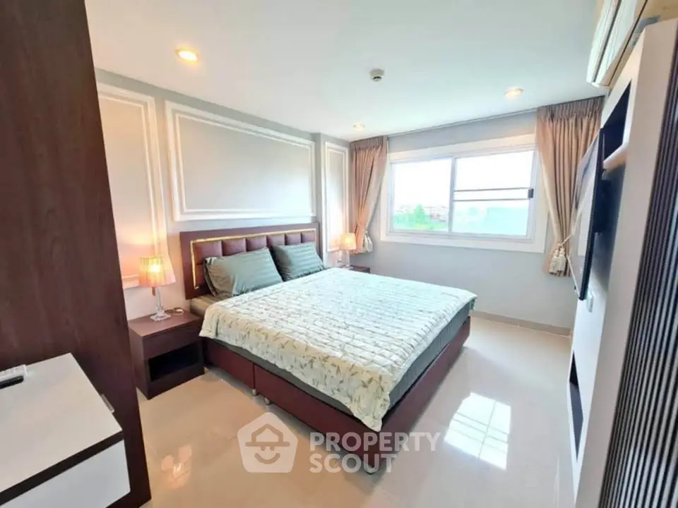 Spacious bedroom with modern decor and large window offering natural light.