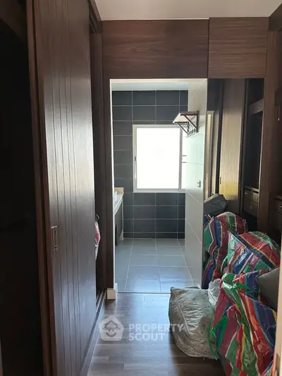 Modern hallway with wooden accents leading to a sleek bathroom with large window.