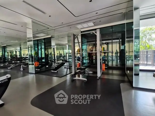Modern gym with mirrored walls and state-of-the-art fitness equipment in luxury apartment complex.