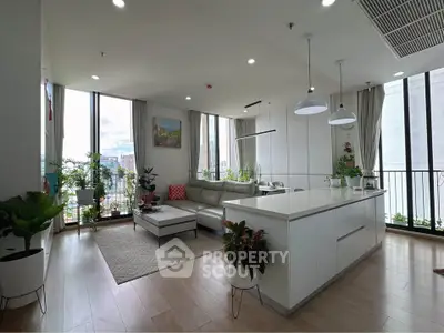 Spacious modern living room with open kitchen and large windows offering city views.