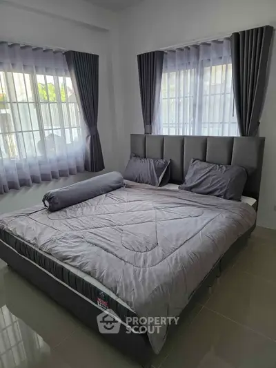 Modern bedroom with stylish gray bedding and large windows for natural light.