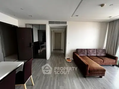 Spacious modern living room with sleek flooring and stylish brown sofa in a contemporary apartment.