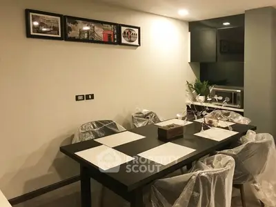Modern dining area with sleek black table and chairs, featuring contemporary decor and ambient lighting.