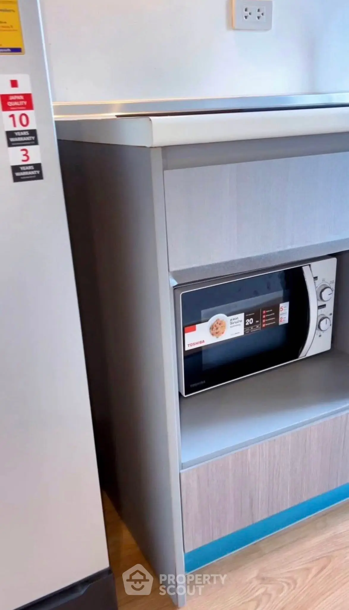 Modern kitchen with sleek microwave and refrigerator, showcasing efficient use of space.