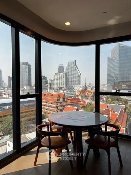 Stunning city view from a modern high-rise apartment with floor-to-ceiling windows and stylish dining area.