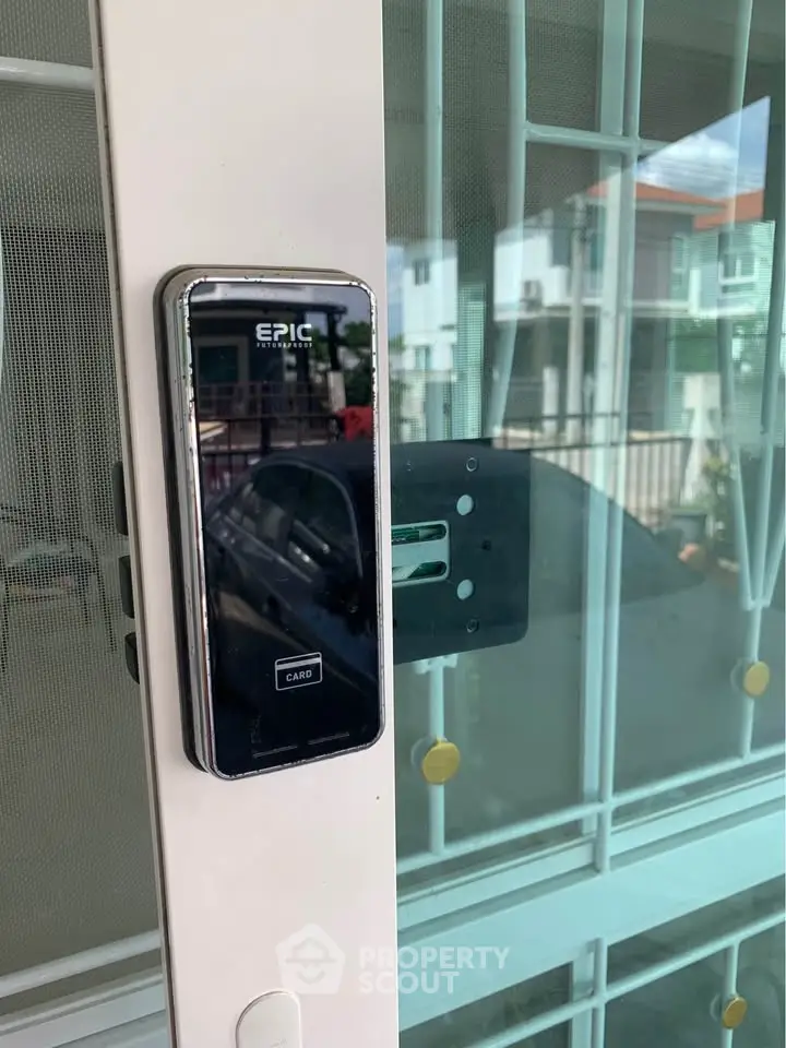 Modern smart lock on a secure glass door with a view of residential neighborhood.