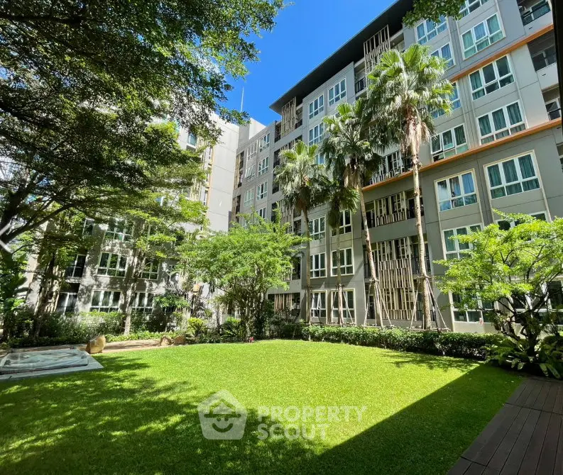 Modern apartment building with lush garden and palm trees, offering serene living environment.