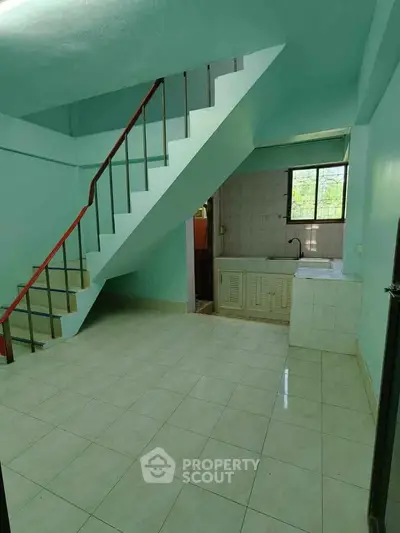 Spacious interior with staircase and tiled flooring, featuring a compact kitchen area.