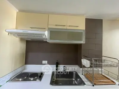 Compact kitchen with electric stove and dish rack, ideal for modern apartment living.