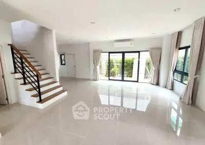 Spacious modern living room with large windows and staircase, perfect for family gatherings.
