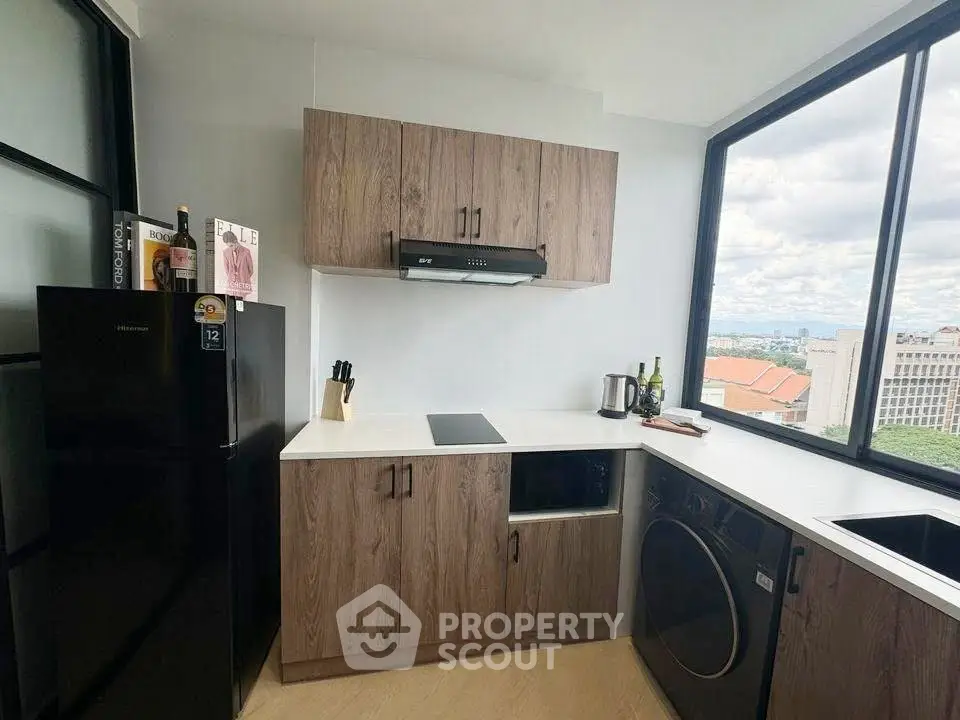 Modern kitchen with sleek cabinetry, large window view, and integrated appliances in urban apartment.