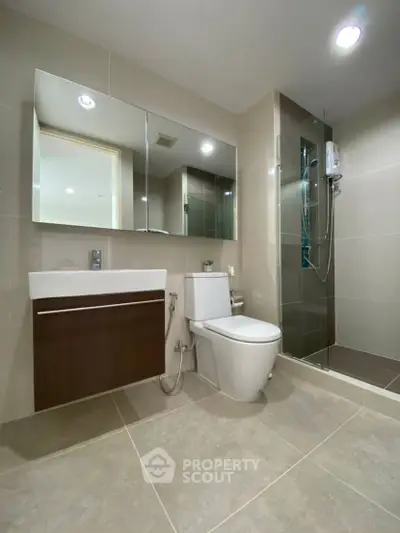 Modern bathroom with sleek fixtures and glass shower enclosure, featuring a minimalist design.
