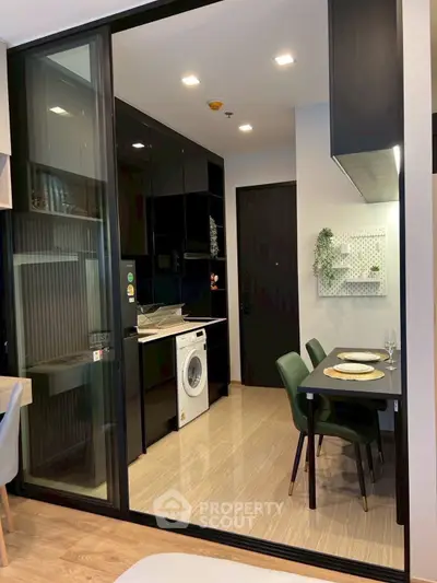 Modern kitchen with sleek black cabinets and integrated washing machine in stylish apartment.