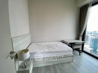 Modern bedroom with city view, featuring sleek furniture and large window for natural light.