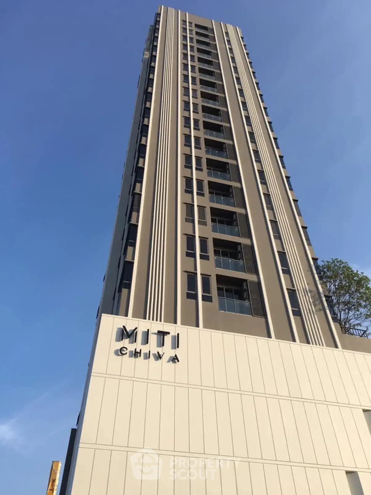 Modern high-rise building with sleek design and vertical lines under a clear blue sky.