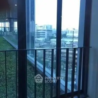 Stunning city view from modern building balcony with lush greenery.