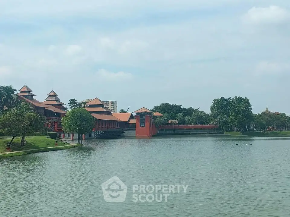Stunning lakeside view of traditional architecture with lush greenery and serene water reflections.