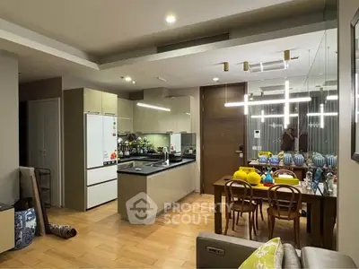 Modern open-layout kitchen and dining area with sleek lighting and wooden flooring.