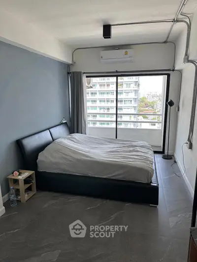 Spacious bedroom with modern decor and large window offering city views