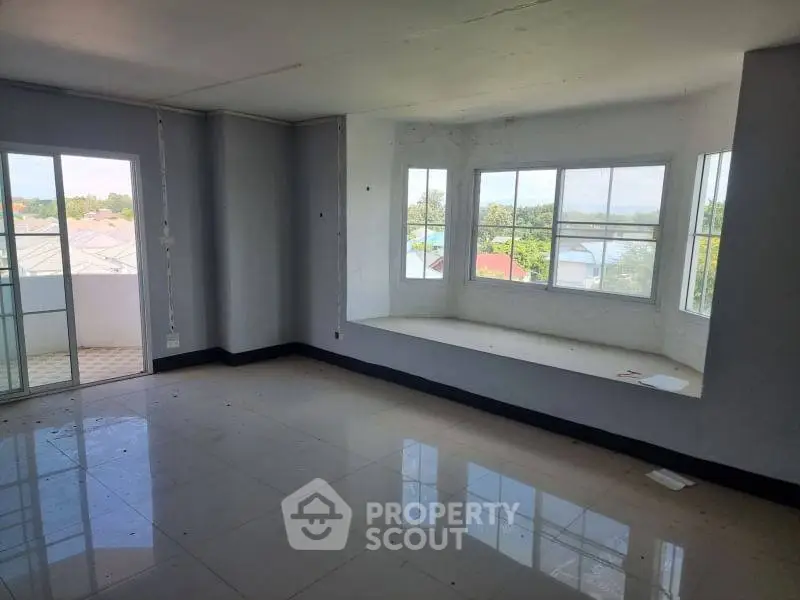 Spacious living room with large windows and balcony access, offering abundant natural light and scenic views.