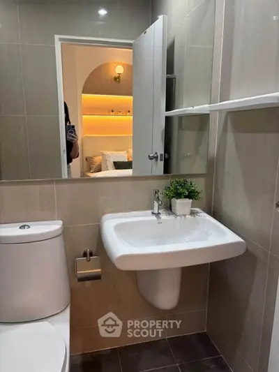 Modern bathroom with sleek fixtures and a glimpse into a cozy bedroom, showcasing elegant design.
