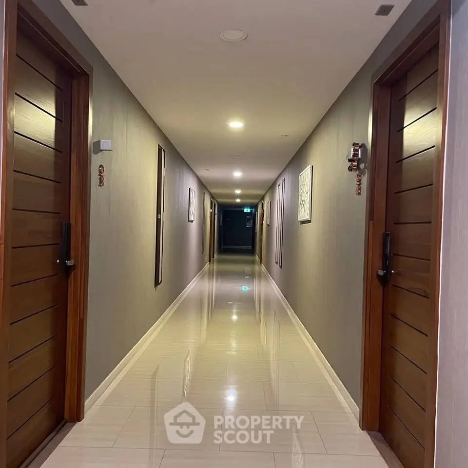 Modern apartment corridor with polished floors and wooden doors, offering a sleek and inviting ambiance.