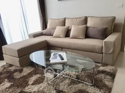 Stylish living room with modern beige sofa and glass coffee table on plush rug.