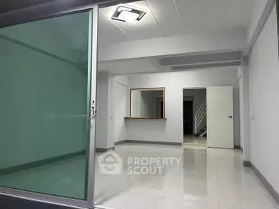 Spacious modern interior with sleek glass partition and minimalist design, ideal for versatile living or office space.