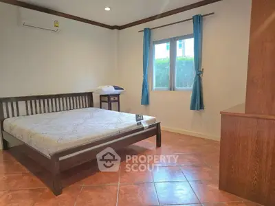 Spacious bedroom with large window and wooden furniture, perfect for comfort and relaxation.