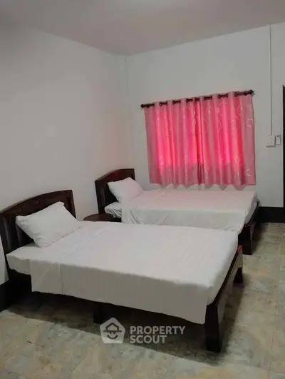 Cozy bedroom with twin beds and vibrant curtains, perfect for a comfortable stay.