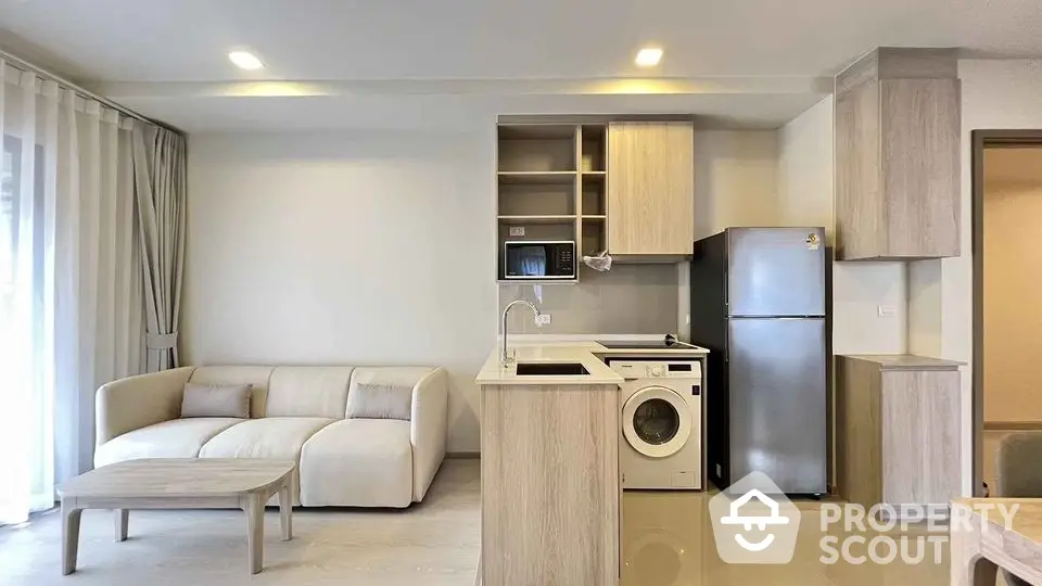 Modern open-plan living room with kitchen, featuring sleek appliances and cozy sofa.