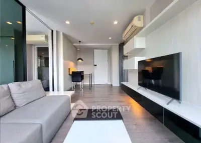 Modern living room with sleek design, featuring a large TV and comfortable seating in a stylish apartment.