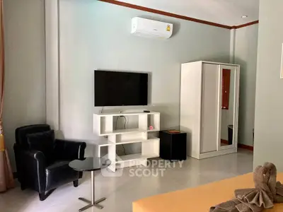 Modern living room with sleek furniture and wall-mounted TV, featuring air conditioning.