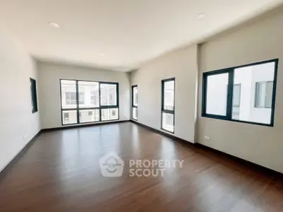 Spacious modern living room with large windows and wooden flooring in a contemporary home.