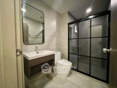 Modern bathroom with sleek design, featuring a glass shower enclosure and contemporary fixtures.