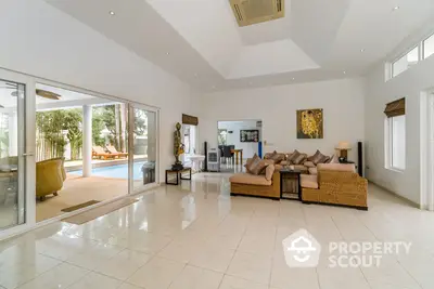 Spacious living room with glossy tiled floors, large windows, and direct pool access, perfect for luxurious indoor-outdoor living.