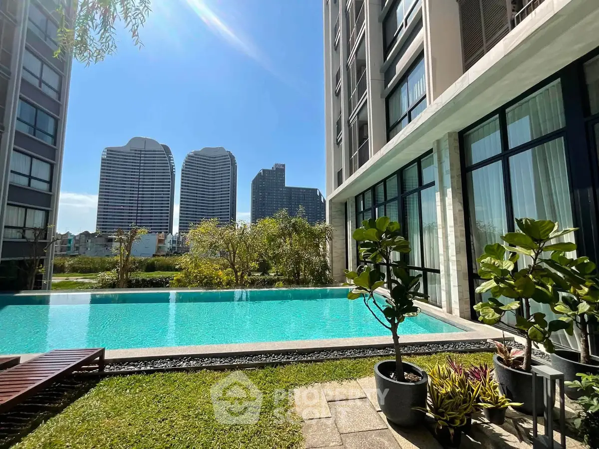 Luxurious apartment complex with stunning pool and city skyline view, perfect for urban living.