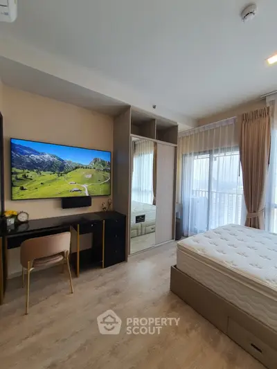 Modern bedroom with large TV and balcony view, featuring stylish decor and ample natural light.