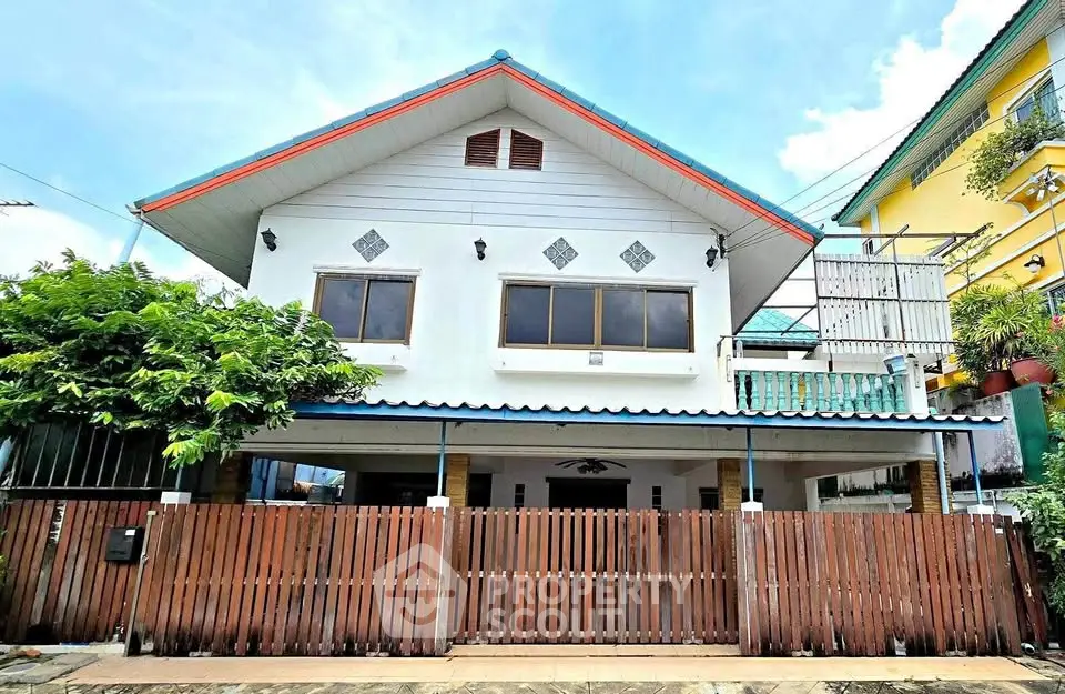 Charming two-story house with wooden fence and lush greenery, perfect for family living.