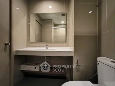 Modern bathroom with sleek fixtures and large mirror in contemporary apartment.