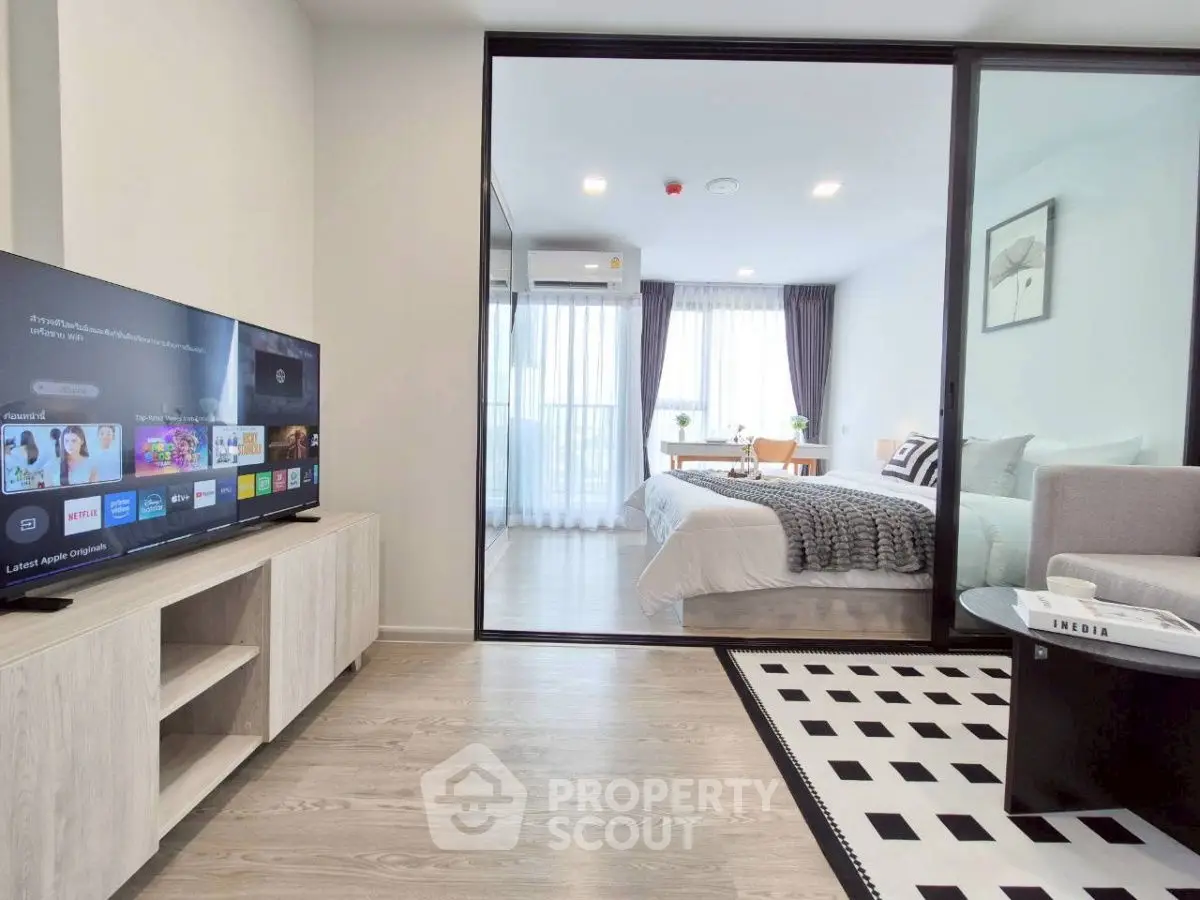 Modern living room with TV and view into stylish bedroom