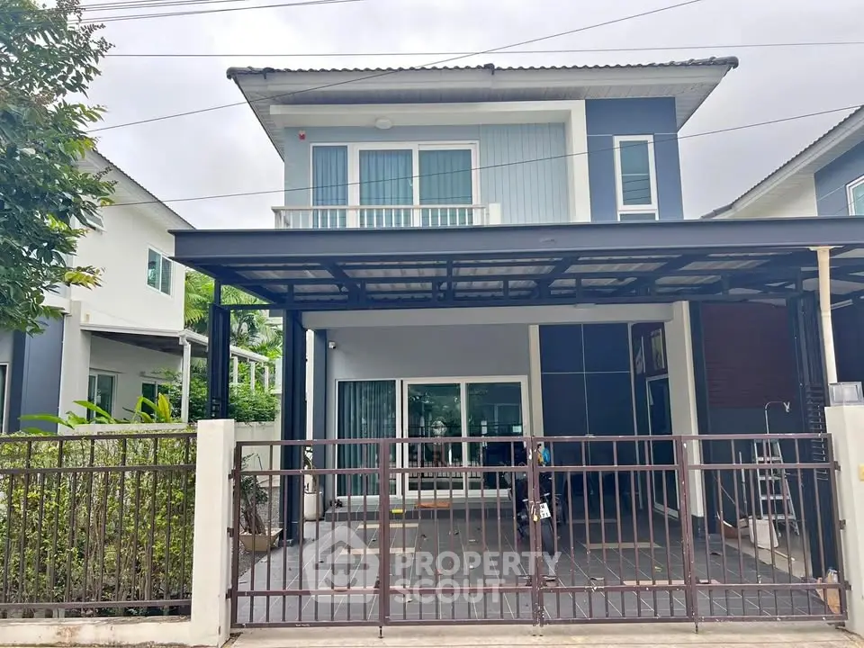 Modern two-story house with covered carport and gated entrance in a suburban neighborhood.