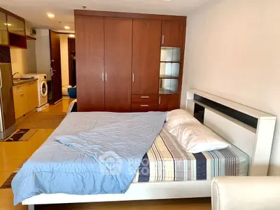 Spacious bedroom with modern furniture and in-unit washing machine, perfect for urban living.