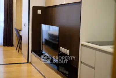 Modern living room with sleek TV setup and stylish wooden flooring.