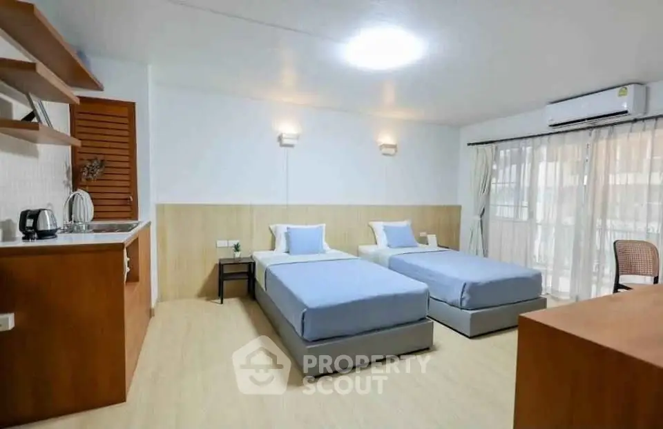 Spacious bedroom with twin beds and kitchenette in modern apartment