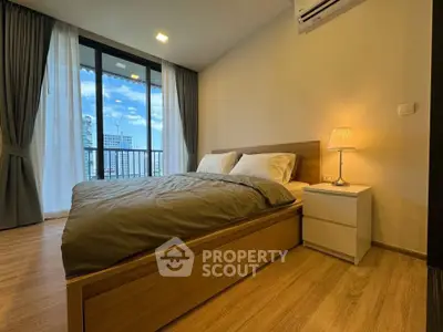 Modern bedroom with city view, featuring wooden flooring and stylish decor.