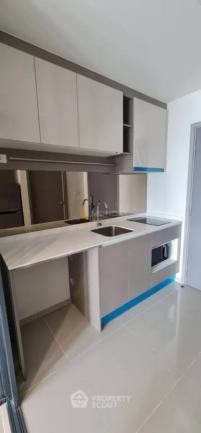 Modern kitchen with sleek cabinetry and built-in microwave in a stylish apartment.