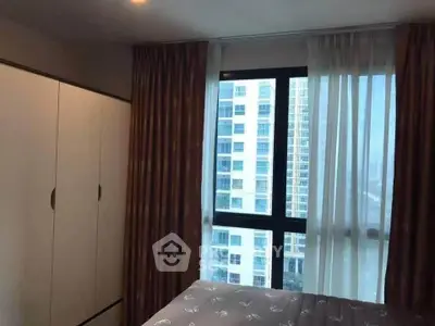 Cozy bedroom with large window offering city view in modern apartment