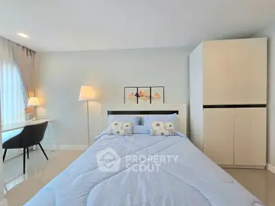 Modern bedroom with stylish decor and ample natural light, featuring a cozy bed and sleek furniture.